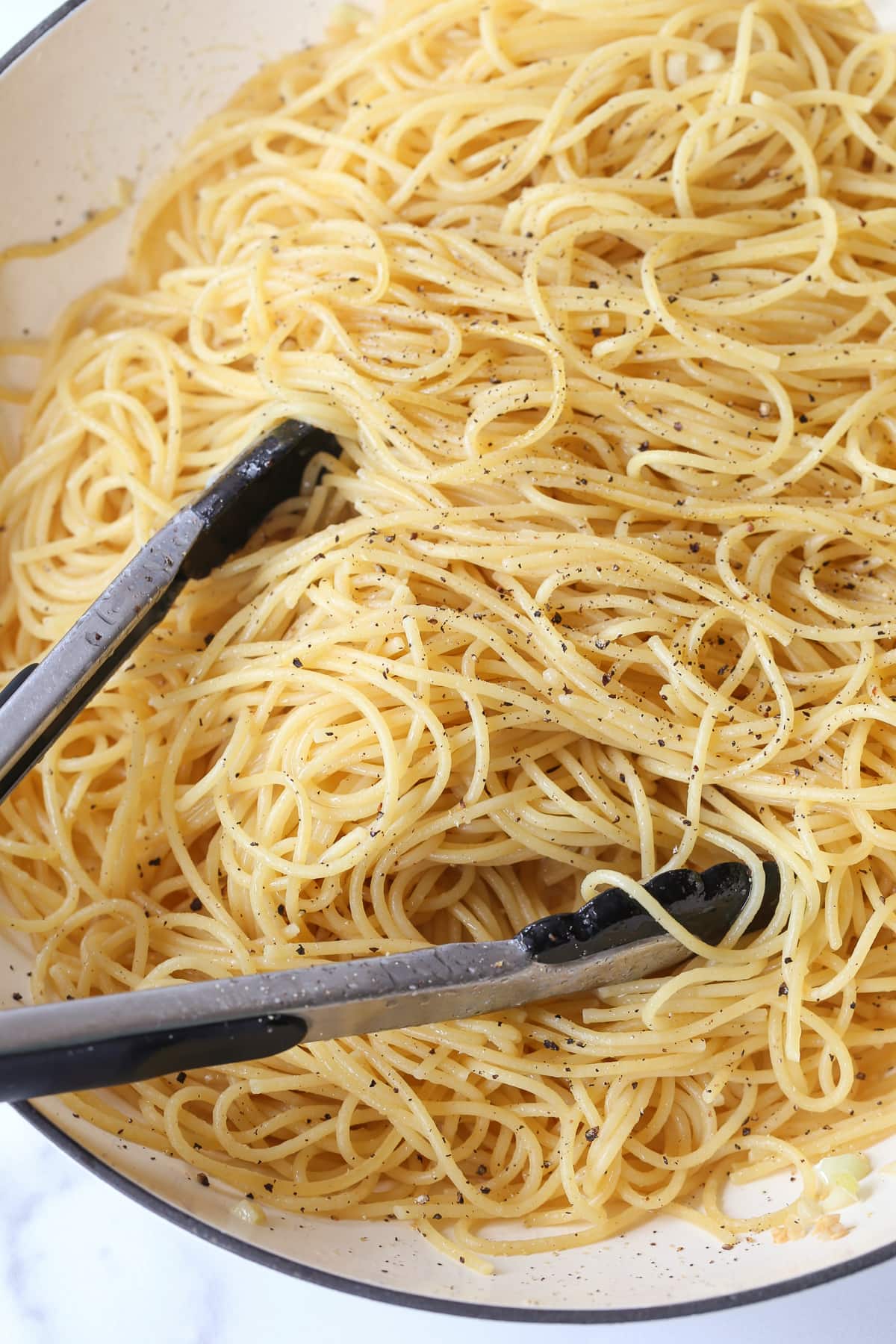 Spaghetti with ground pepper and tongs