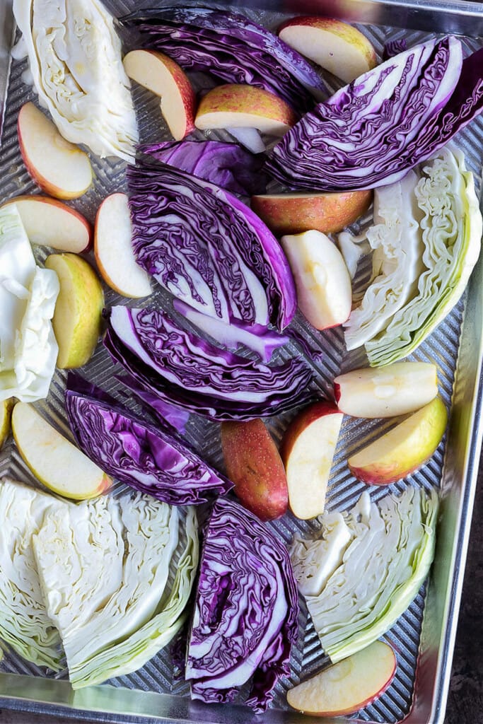 wedged cabbage on a sheet pan with apples