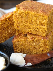 pumpkin cornbread stacked on a plate with a butter knife