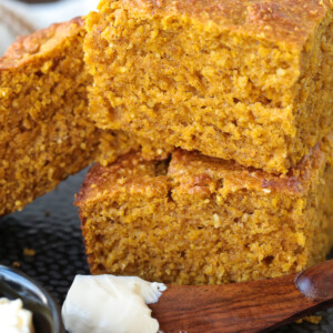 pumpkin cornbread stacked on a plate with a butter knife