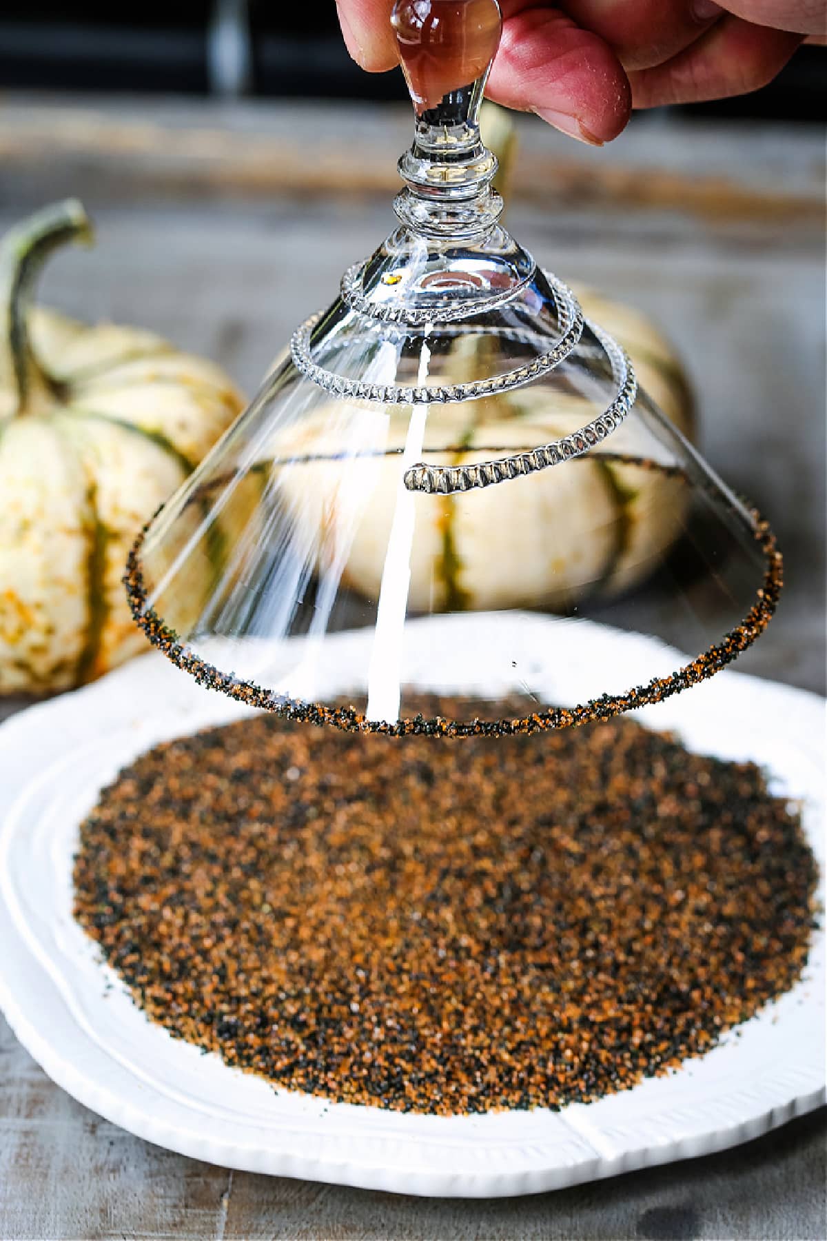 A Pumpkin Spice Martini is a delicious cocktail for your Halloween and Thanksgiving parties! A festive, fun cocktail that's sure to be a hit! a martini glass being dipped into a plate of sugar