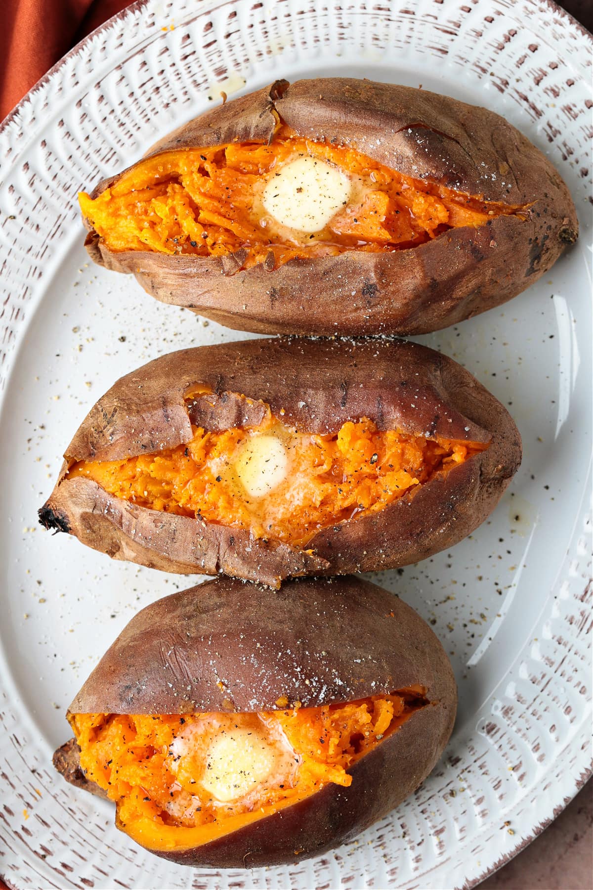 sweet potatoes on a white platter cut open with butter