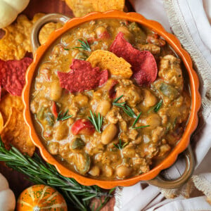 Turkey chili in an orange bowl with pumpkin around