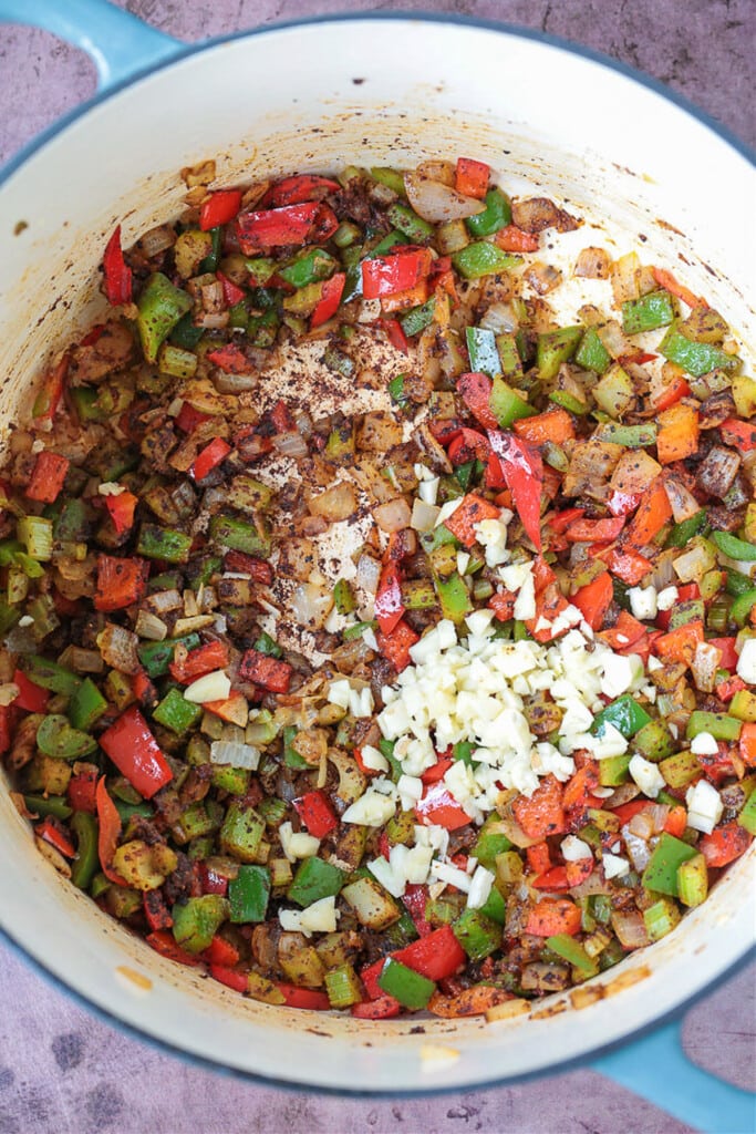 This cozy Pumpkin Chili recipe is giving all the fall vibes! A creamy, hearty turkey chili simmered with pumpkin puree, white wine and beans! peppers, onions and garlic in a pot for making turkey chili