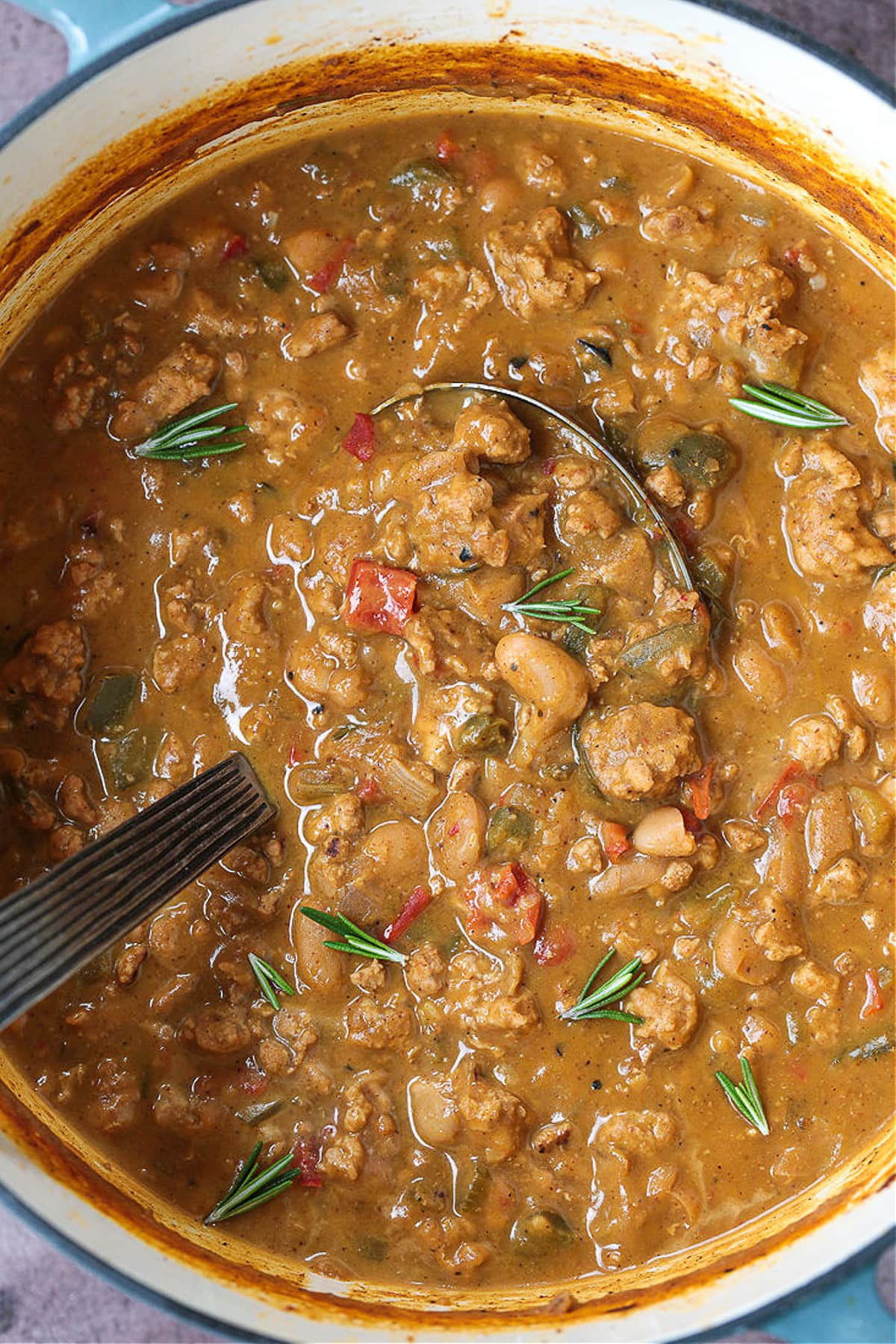 This cozy Pumpkin Chili recipe is giving all the fall vibes! A creamy, hearty turkey chili simmered with pumpkin puree, white wine and beans! turkey pumpkin chili in a pot with ladle