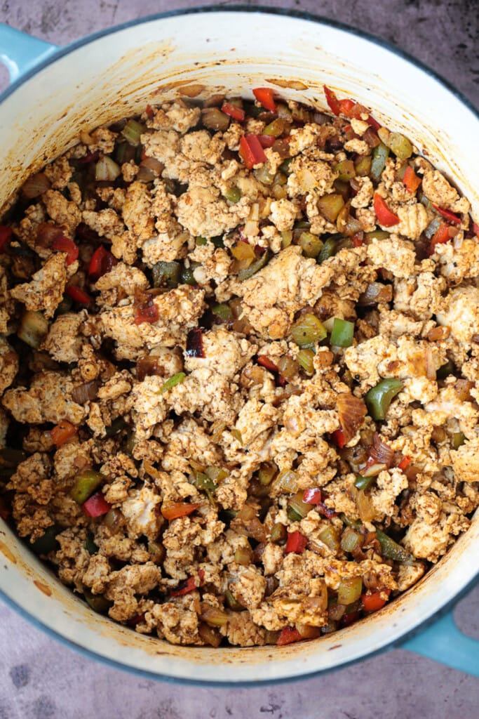 This cozy Pumpkin Chili recipe is giving all the fall vibes! A creamy, hearty turkey chili simmered with pumpkin puree, white wine and beans! ground turkey, peppers and onions in a pot for chili recipe