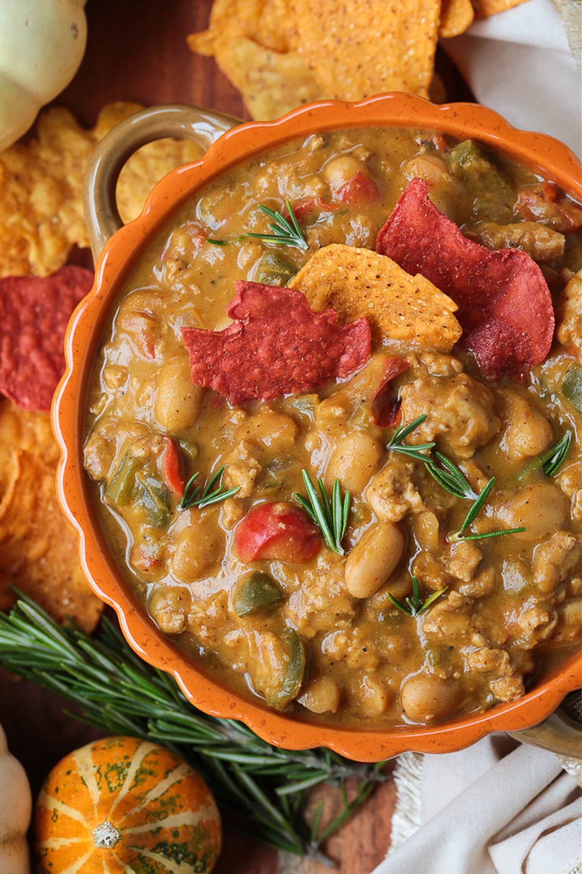 This cozy Pumpkin Chili recipe is giving all the fall vibes! A creamy, hearty turkey chili simmered with pumpkin puree, white wine and beans! turkey pumpkin chili in orange bowl with tortilla chips