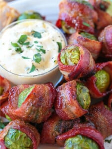 brussels sprouts wrapped in bacon on plate with sauce