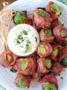 bacon wrapped brussels sprouts on white plate with sauce