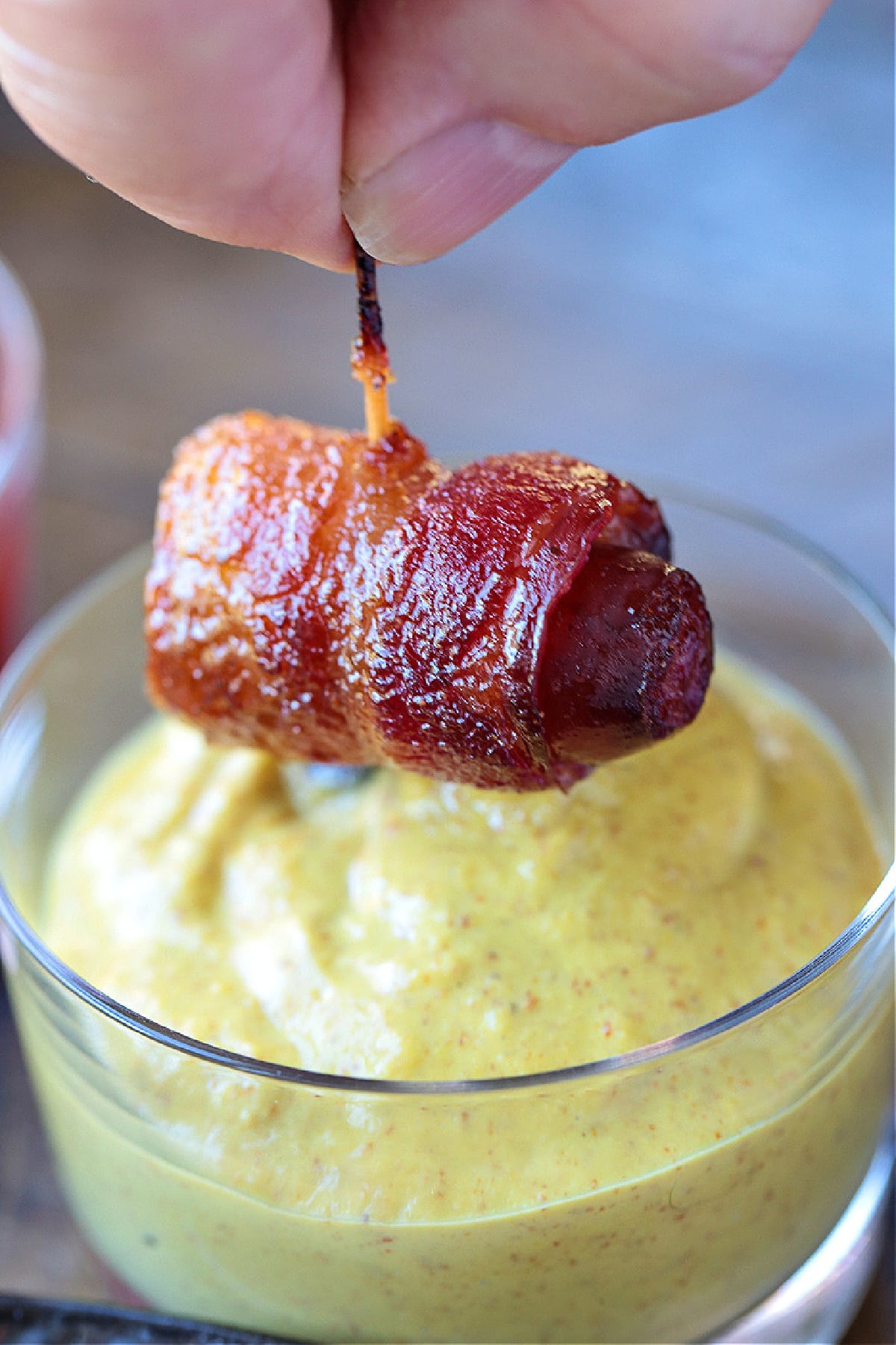 Bacon Wrapped Smokies are an addicting one-bite appetizer that everyone loves! Perfect for game days, parties and holidays! bacon wrapped hot dog dipping into mustard
