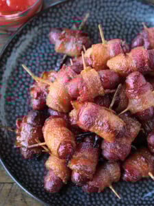 bacon wrapped hot dogs on black plate