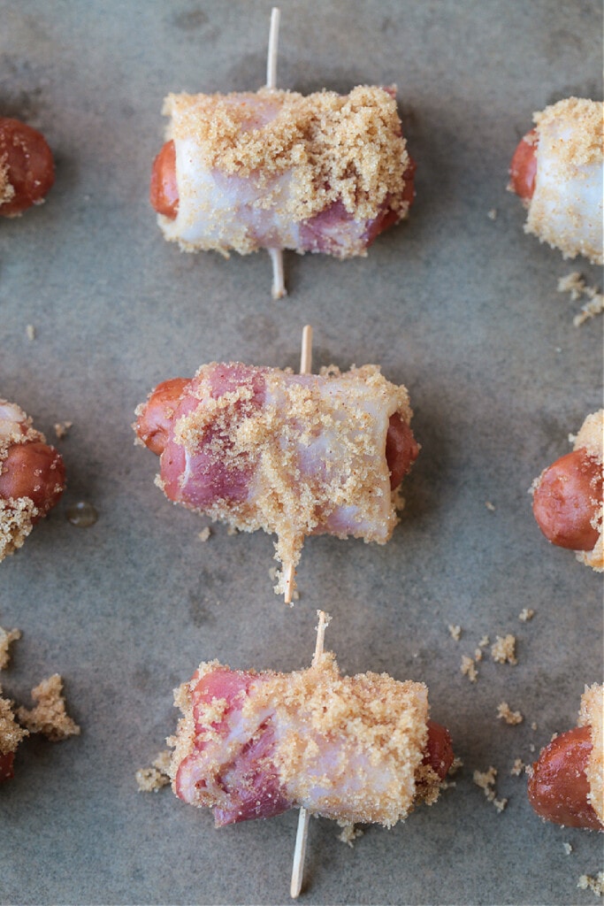 Bacon Wrapped Smokies are an addicting one-bite appetizer that everyone loves! Perfect for game days, parties and holidays! bacon wrapped hot dogs with brown sugar topping on sheet pan