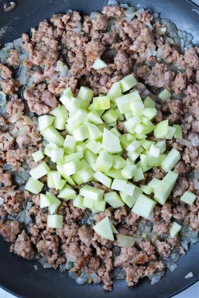 Our Sausage Stuffing Recipe is a favorite at Thanksgiving. Tons of sausage, sweet apples and buttery, toasted bread. We crave it all year! crumbled sausage and apples in skillet
