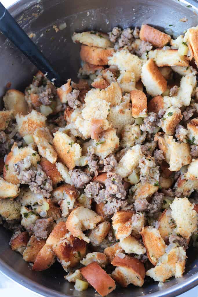 Our Sausage Stuffing Recipe is a favorite at Thanksgiving. Tons of sausage, sweet apples and buttery, toasted bread. We crave it all year! sausage and bread cubes in a bowl for stuffing