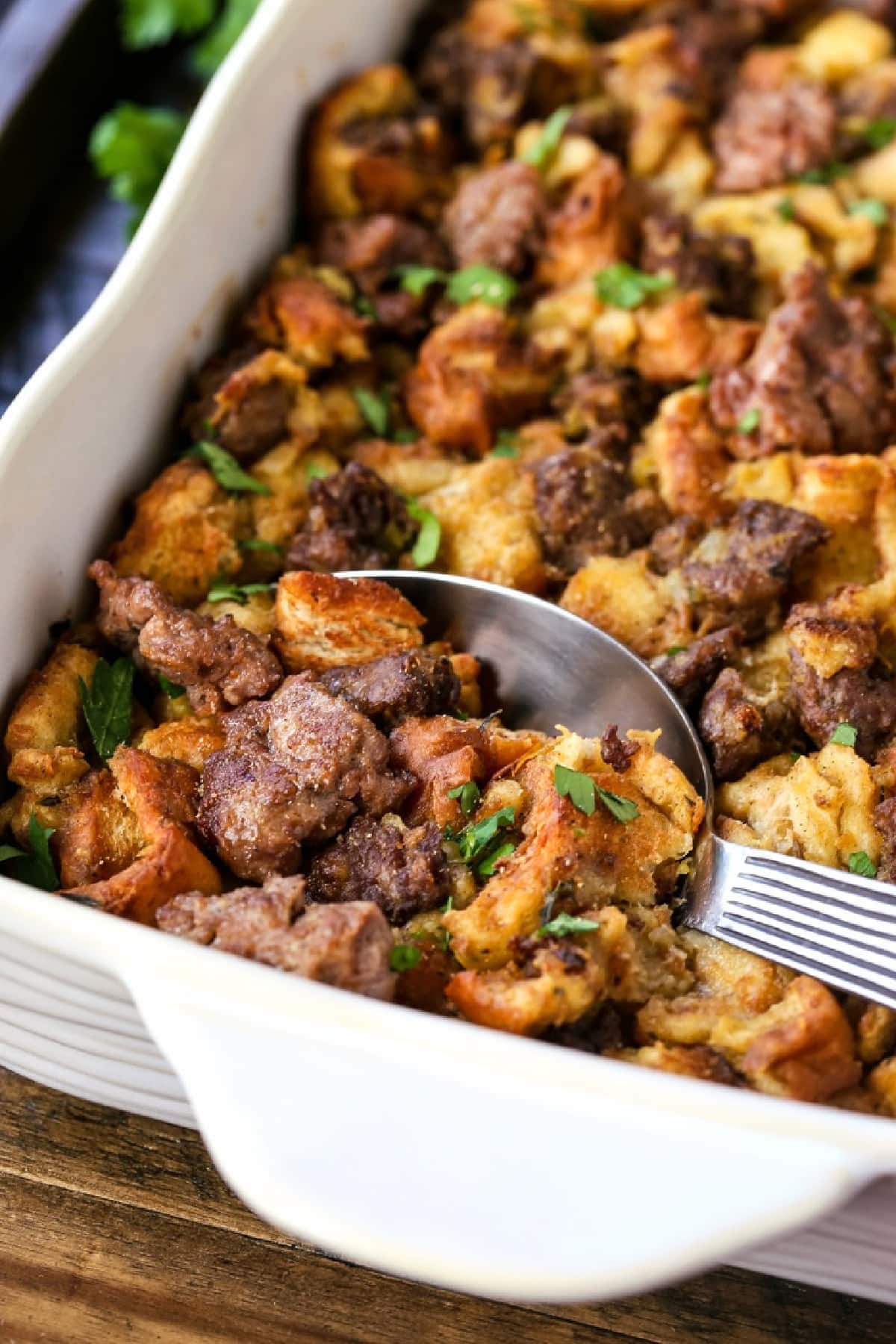 sausage stuffing in baking dish with serving spoon