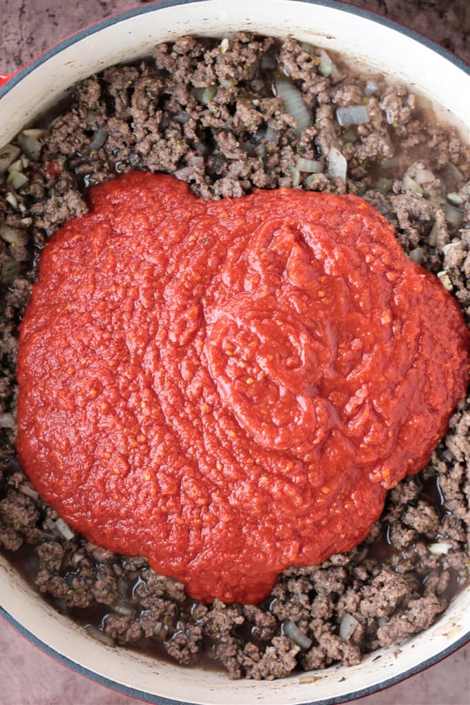 ground beef in a pot with tomato sauce on top