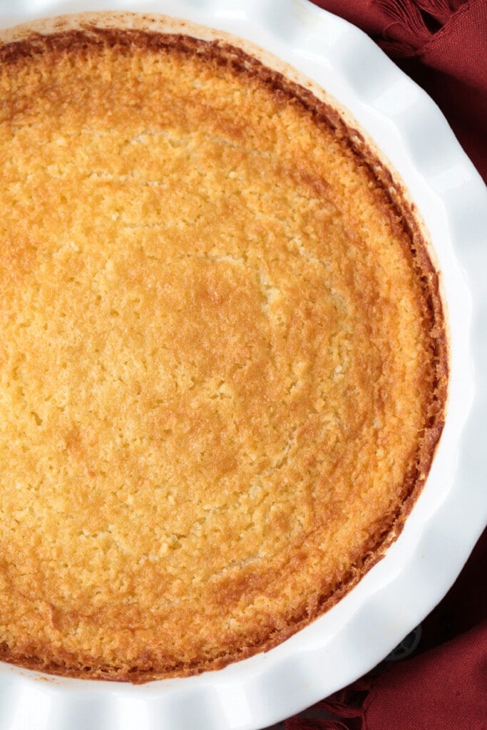Impossible Coconut Pie is so easy to make it seems impossible! A creamy, sweet, custard pie that forms it's own crust as it bakes! coconut pie in white pie dish
