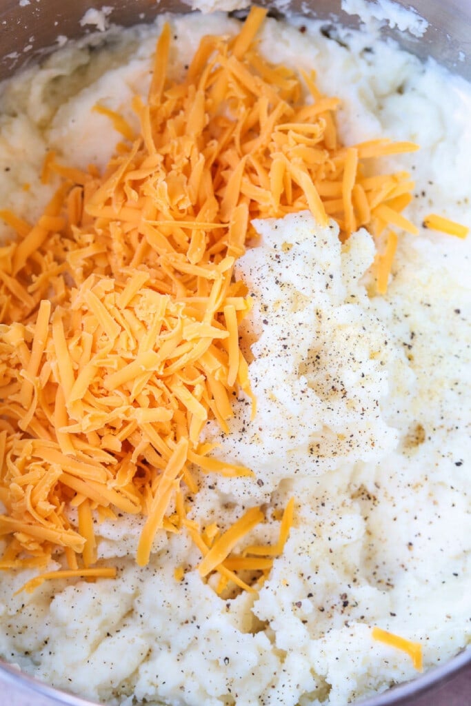 This Loaded Mashed Potato Casserole is so hearty and delicious. A make ahead potato side dish that makes party planning and holidays so easy! mashed potatoes in bowl with shredded cheddar cheese