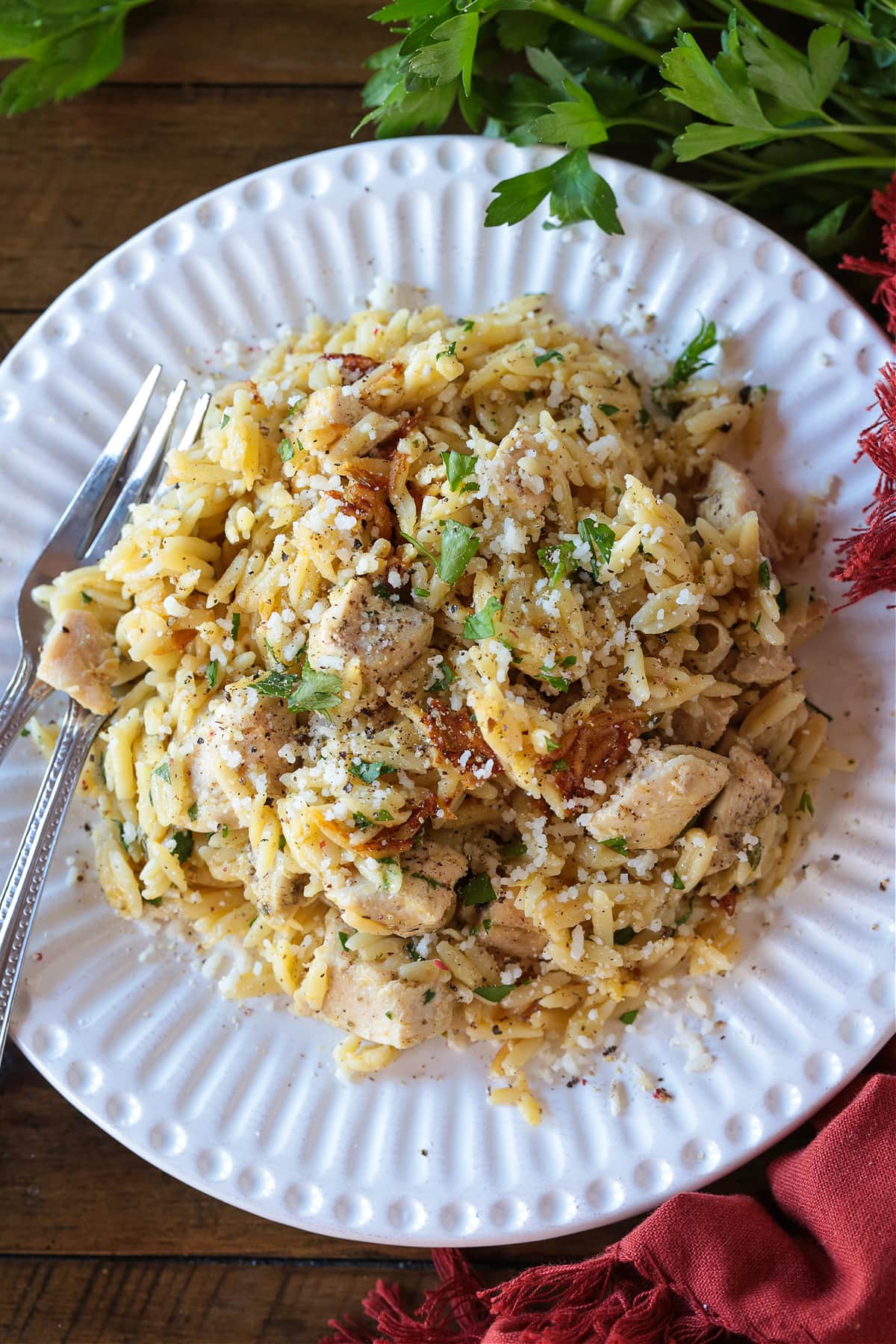 chicken and orzo dinner on white plate with forks and napkin