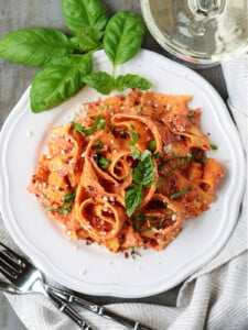 pappardelle in champagne cream sauce on plate with glass of champagne on side