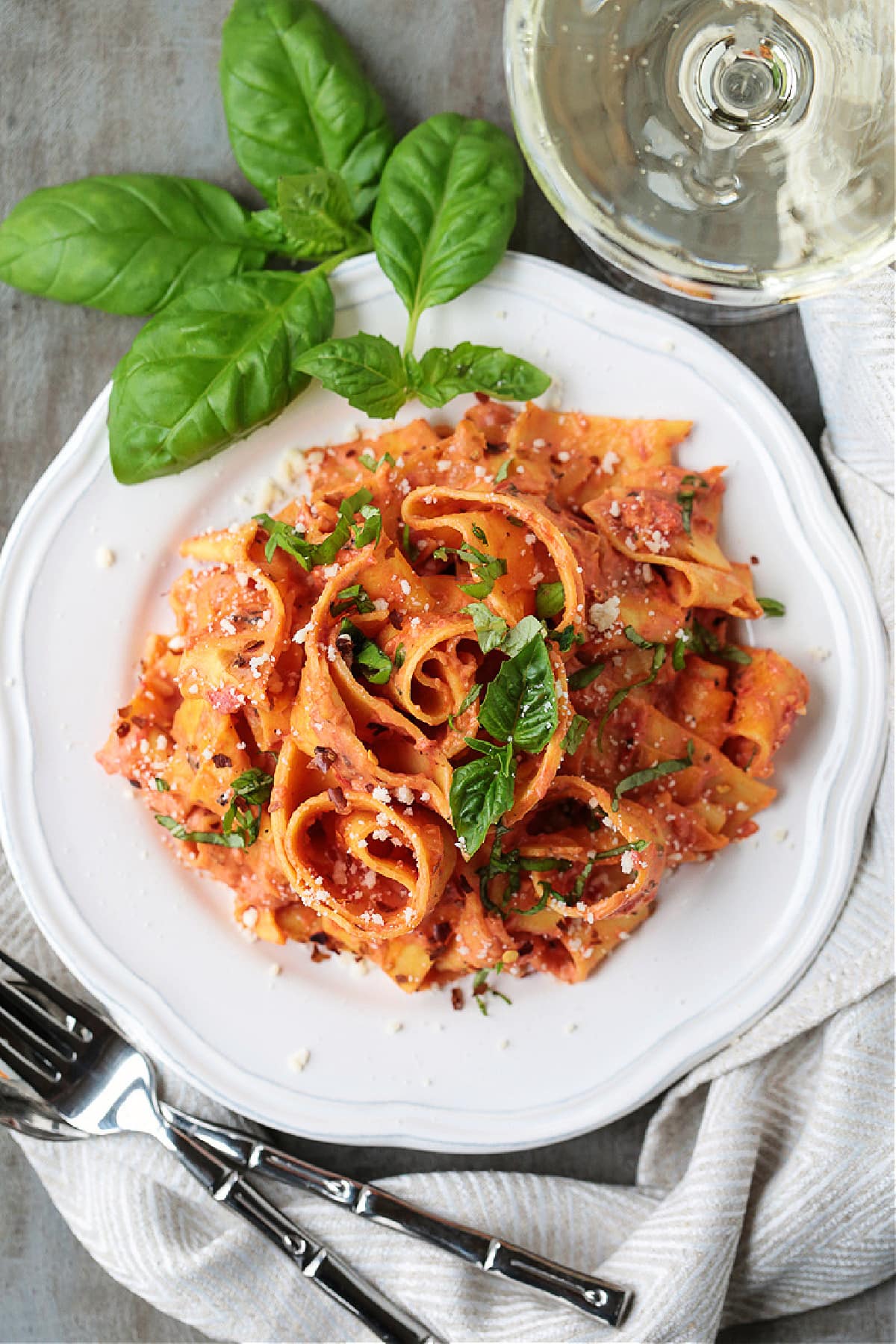 Pappardelle with Champagne Cream Sauce is perfect for the holidays! Pappardelle pasta tossed in a tomato cream sauce with real champagne! pappardelle in champagne cream sauce on plate with glass of champagne on side