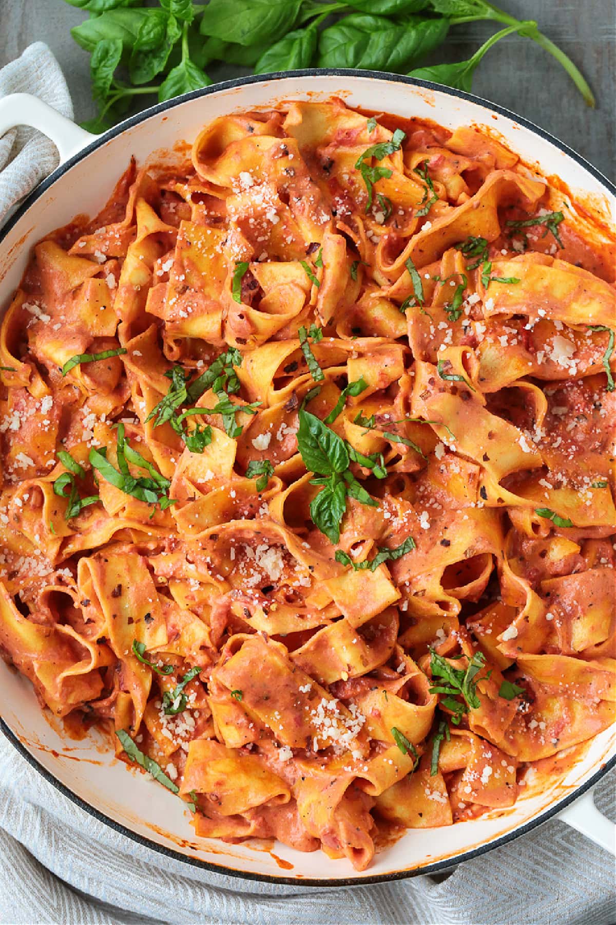 pappardelle pasta in pot with tomato cream sauce and basil