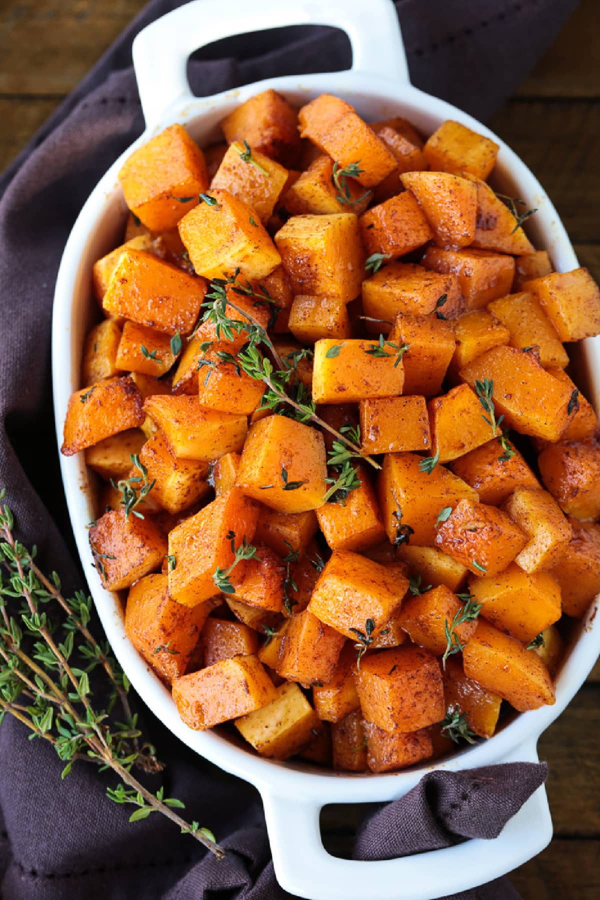 This simple Roasted Butternut Squash is so full of flavor. An easy side dish that goes with just about any dinner, especially a holiday meal! diced butternut squash in baking dish with thyme