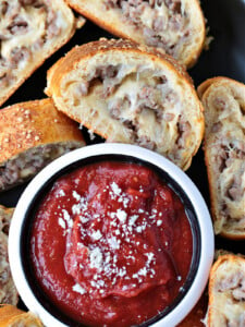 slice of sausage bread dipping into sauce