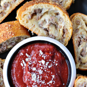 slice of sausage bread dipping into sauce