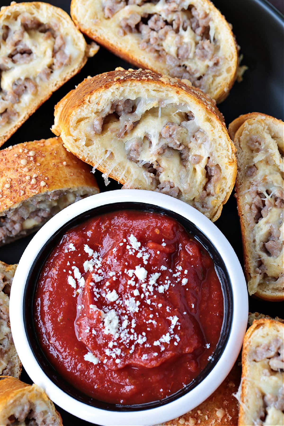 slice of sausage bread dipping into sauce