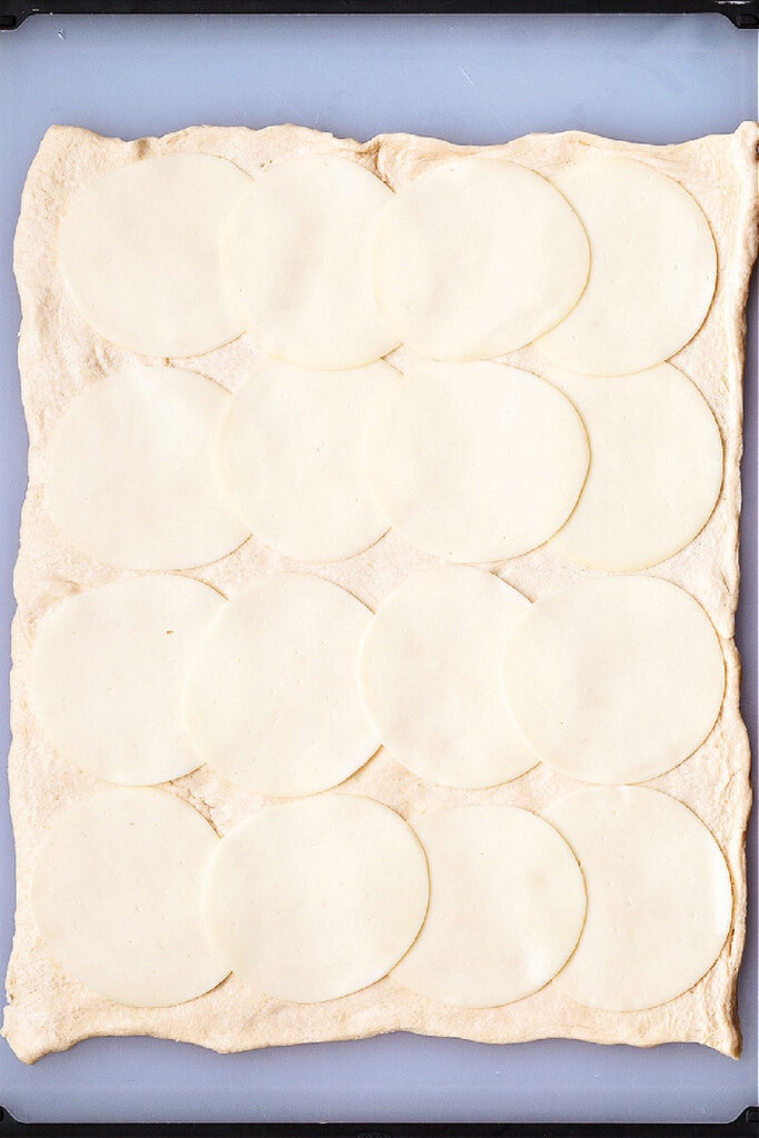slices of mozzarella cheese on crescent roll dough