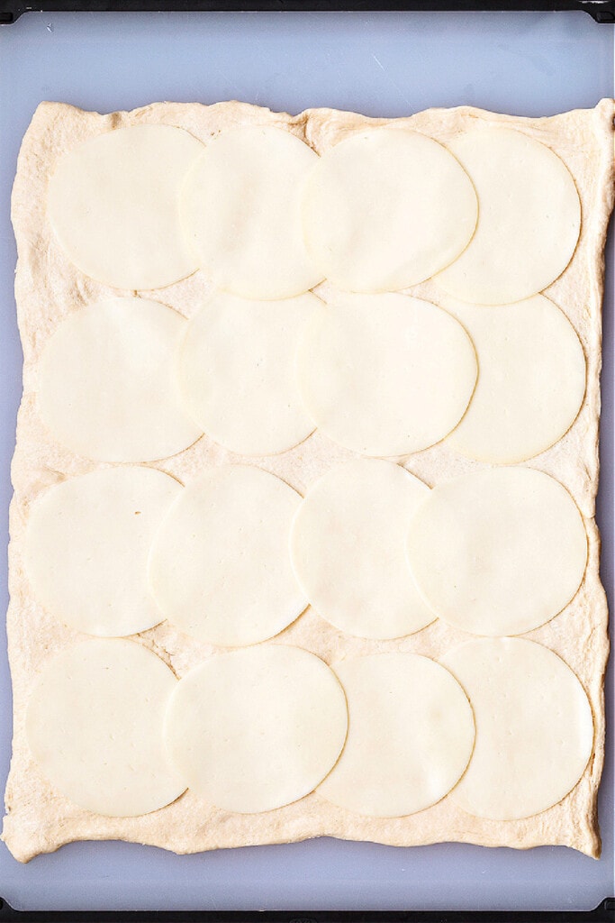 Our Sausage Bread recipe is packed full of sausage and cheese. Slice and serve for appetizers or for a fun dinner night instead of pizza. slices of mozzarella cheese on crescent roll dough