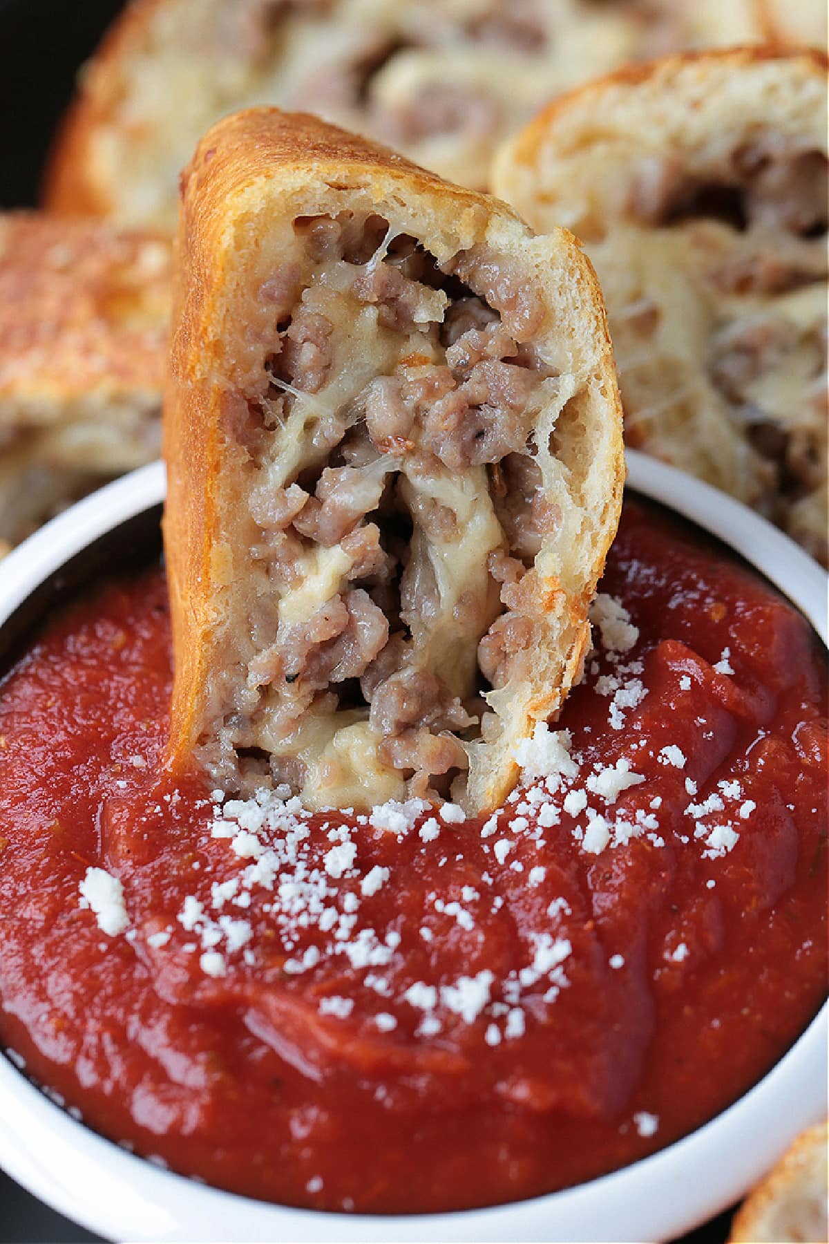 Our Sausage Bread recipe is packed full of sausage and cheese. Slice and serve for appetizers or for a fun dinner night instead of pizza. slice of sausage bread dipped into marinara sauce