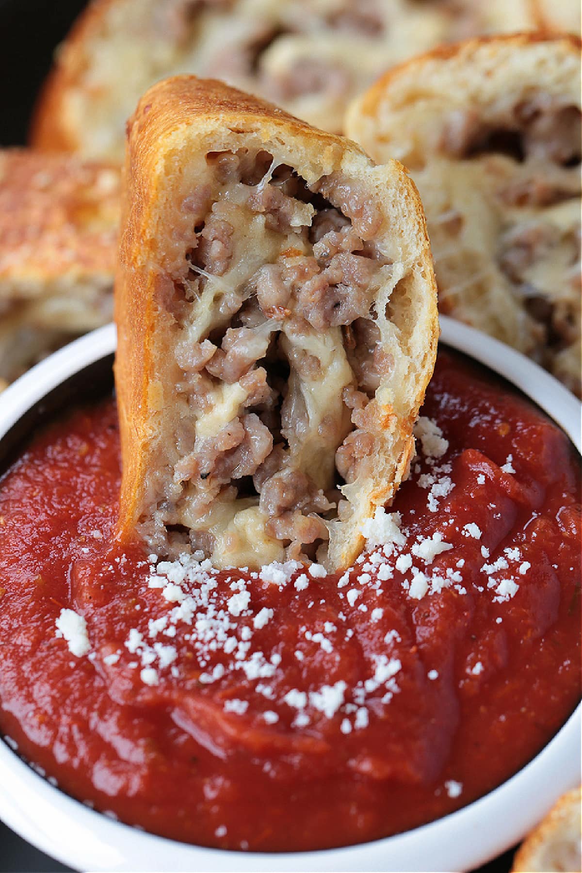 slice of sausage bread dipped into marinara sauce