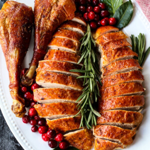 sliced turkey with turkey legs on platter with rosemary