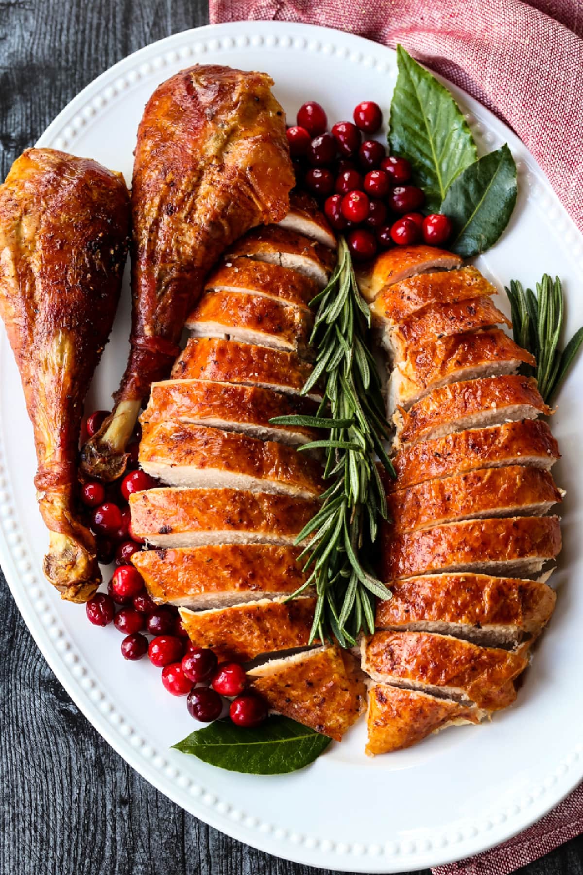 Our Simple Roast Turkey recipe is moist and juicy every time! Don't let a whole turkey scare you, our recipe will make you look like a pro! sliced turkey with turkey legs on platter with rosemary