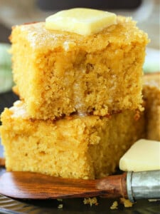 thick slices of cornbread stacked on plate with butter