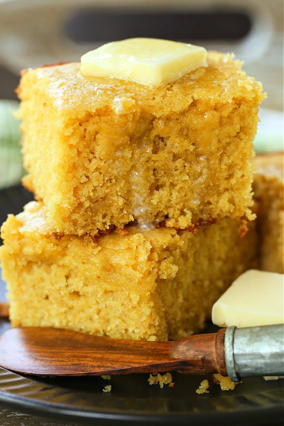 Sweet Cornbread is so moist and addicting. This sweet cornbread recipe is an easy side dish for chili, pulled pork or a holiday ham dinner! thick slices of cornbread stacked on plate with butter