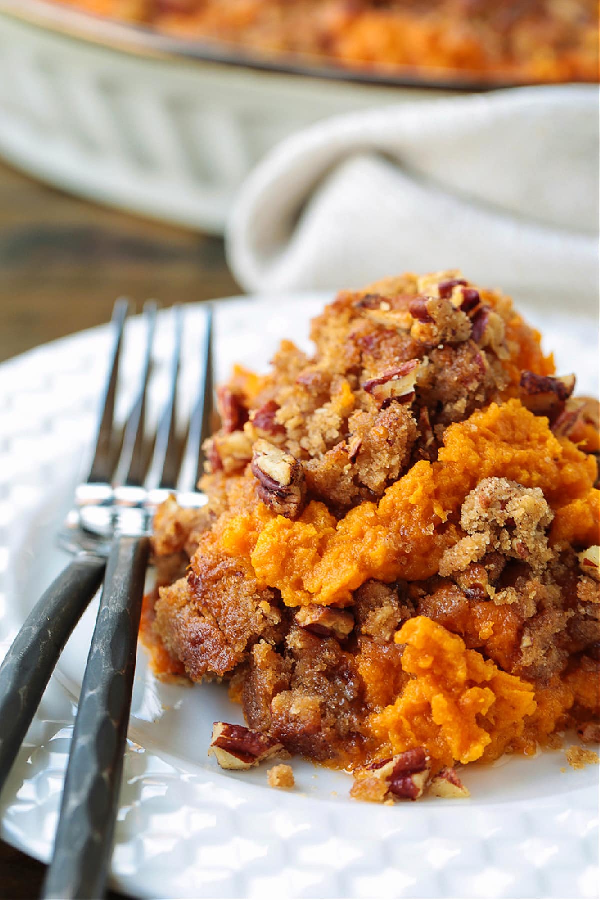Our Sweet Potato Souffle is light and fluffy with a sweet, nutty streusel topping! A make ahead side dish for all of your holiday dinners! sweet potato souffle on plate with fork