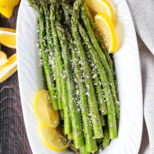 air fryer asparagus on white platter with lemons