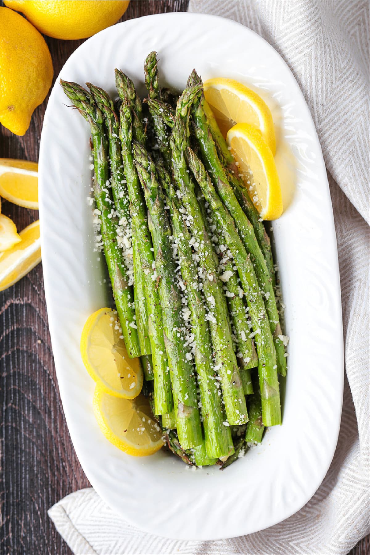 air fryer asparagus on white platter with lemons