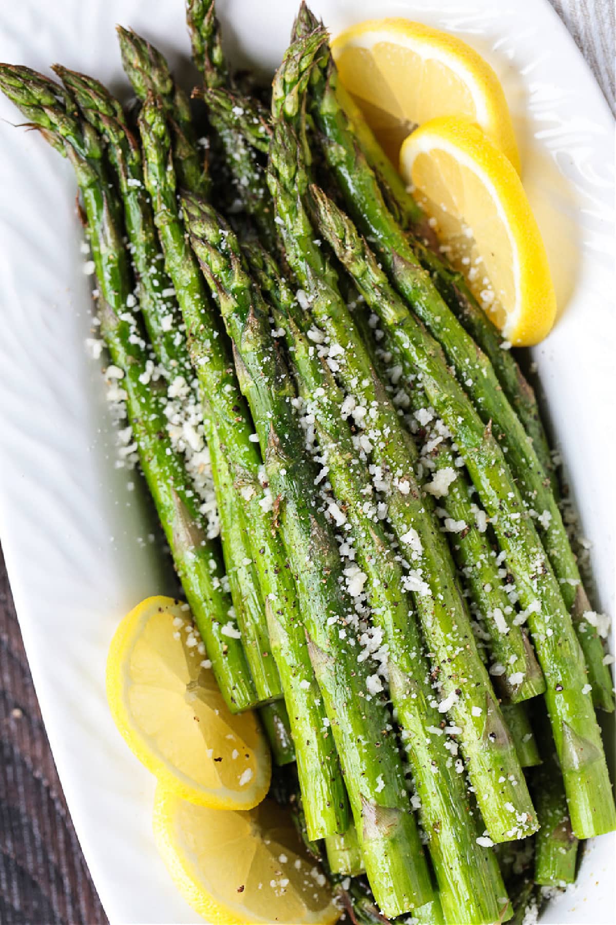 Air Fryer Asparagus is cooked perfectly crisp and tender, and only takes a few minutes in the air fryer. Lightly seasoned and so delicious! asparagus on platter with lemon slices