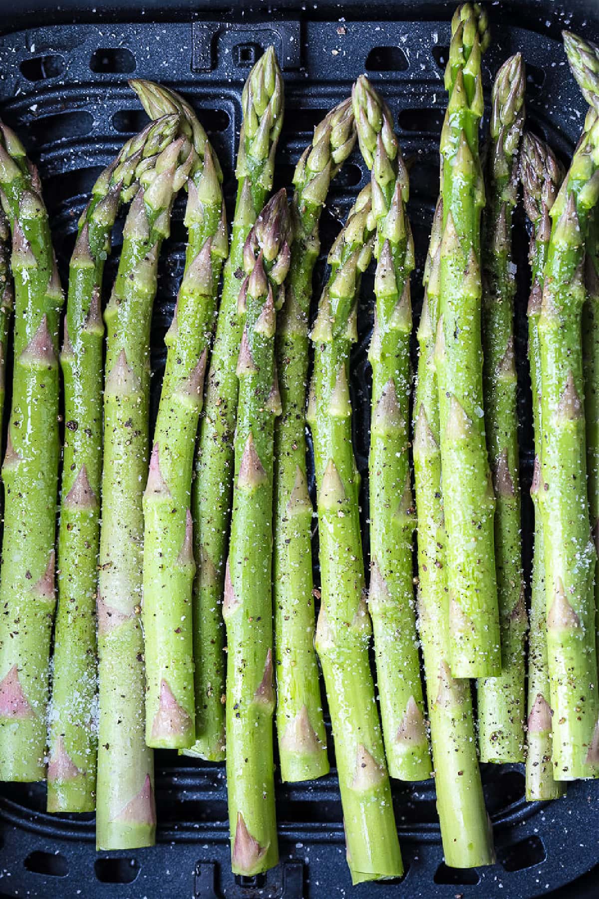 Air Fryer Asparagus is cooked perfectly crisp and tender, and only takes a few minutes in the air fryer. Lightly seasoned and so delicious! raw asparagus stalks in air fryer