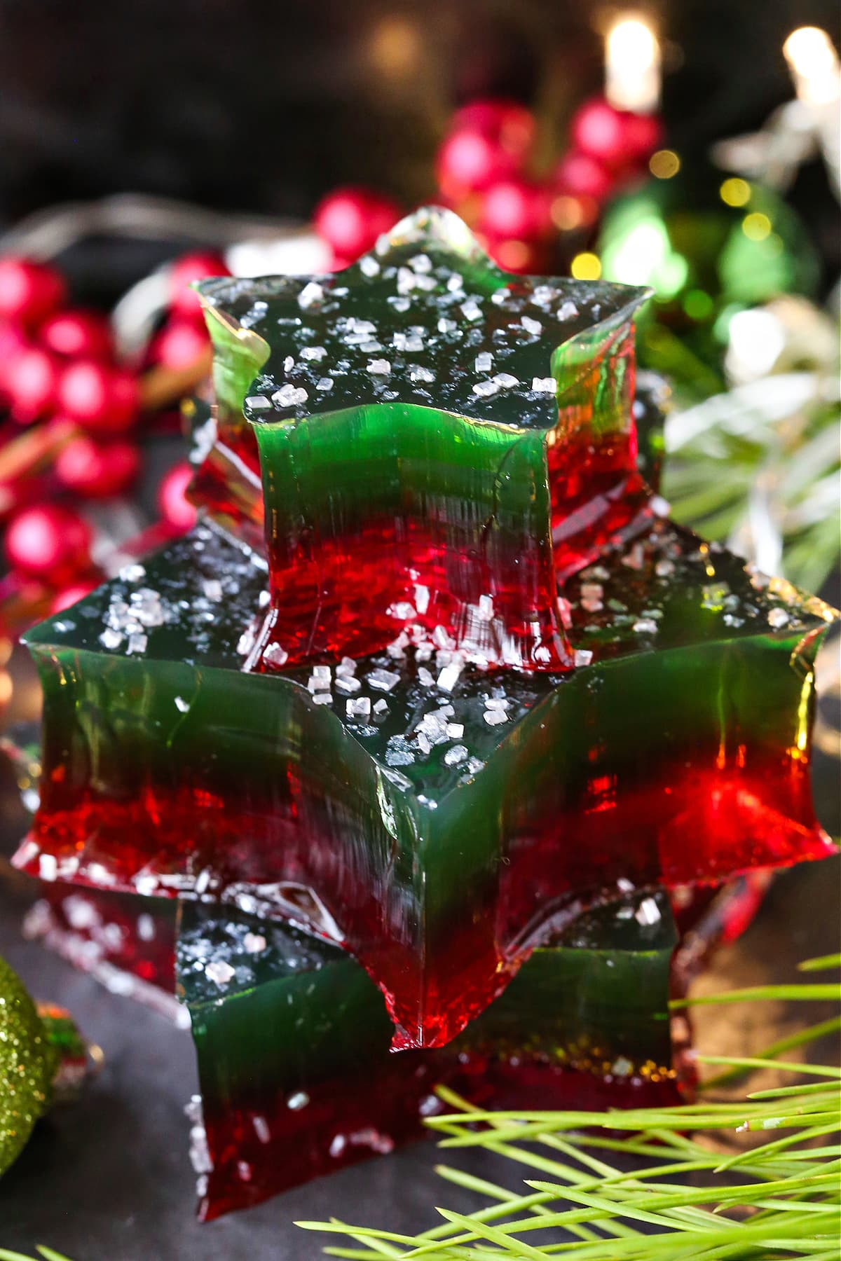 This Christmas Jello Dessert is going to be the star of the party! This festive dessert is made with a splash of real bubbly champagne! christmas colored jello stars stacked with decorations