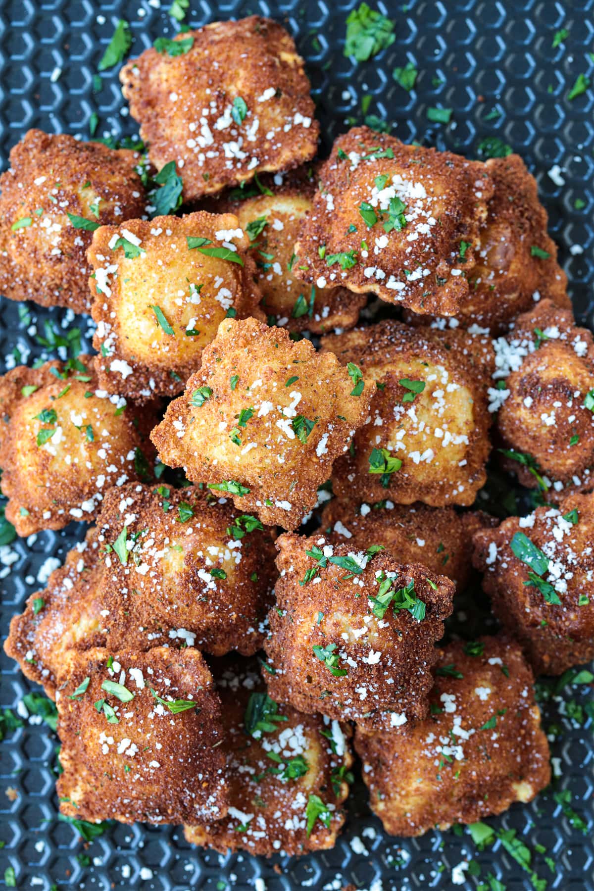 This fried ravioli recipe is crispy on the outside and soft and cheesy on the inside! Dip in marinara sauce for an addicting party appetizer! breaded, fried ravioli on a baking sheet
