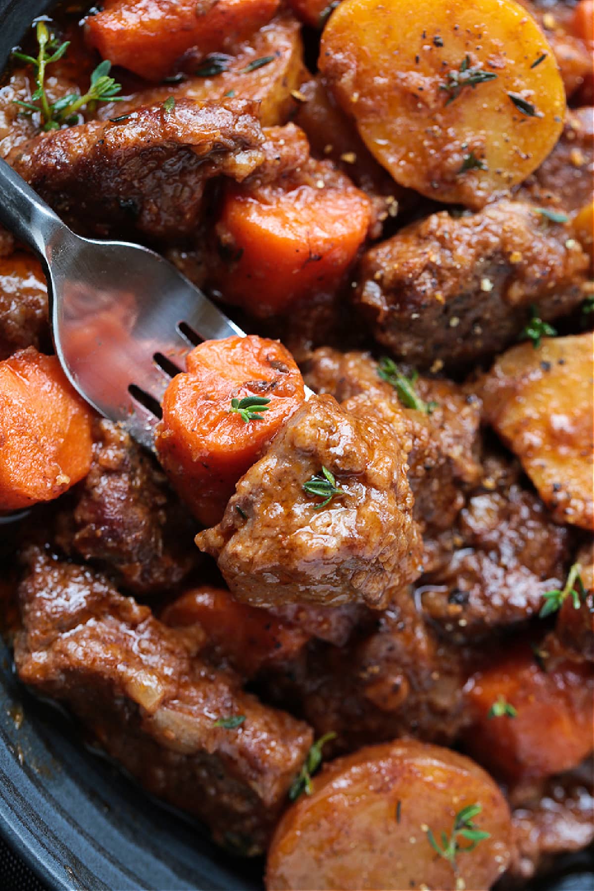 Our Easy Beef Stew is sure to become a family favorite! Tender pieces of beef and vegetables simmered in a red wine and beef gravy. fork grabbing a bite of beef stew