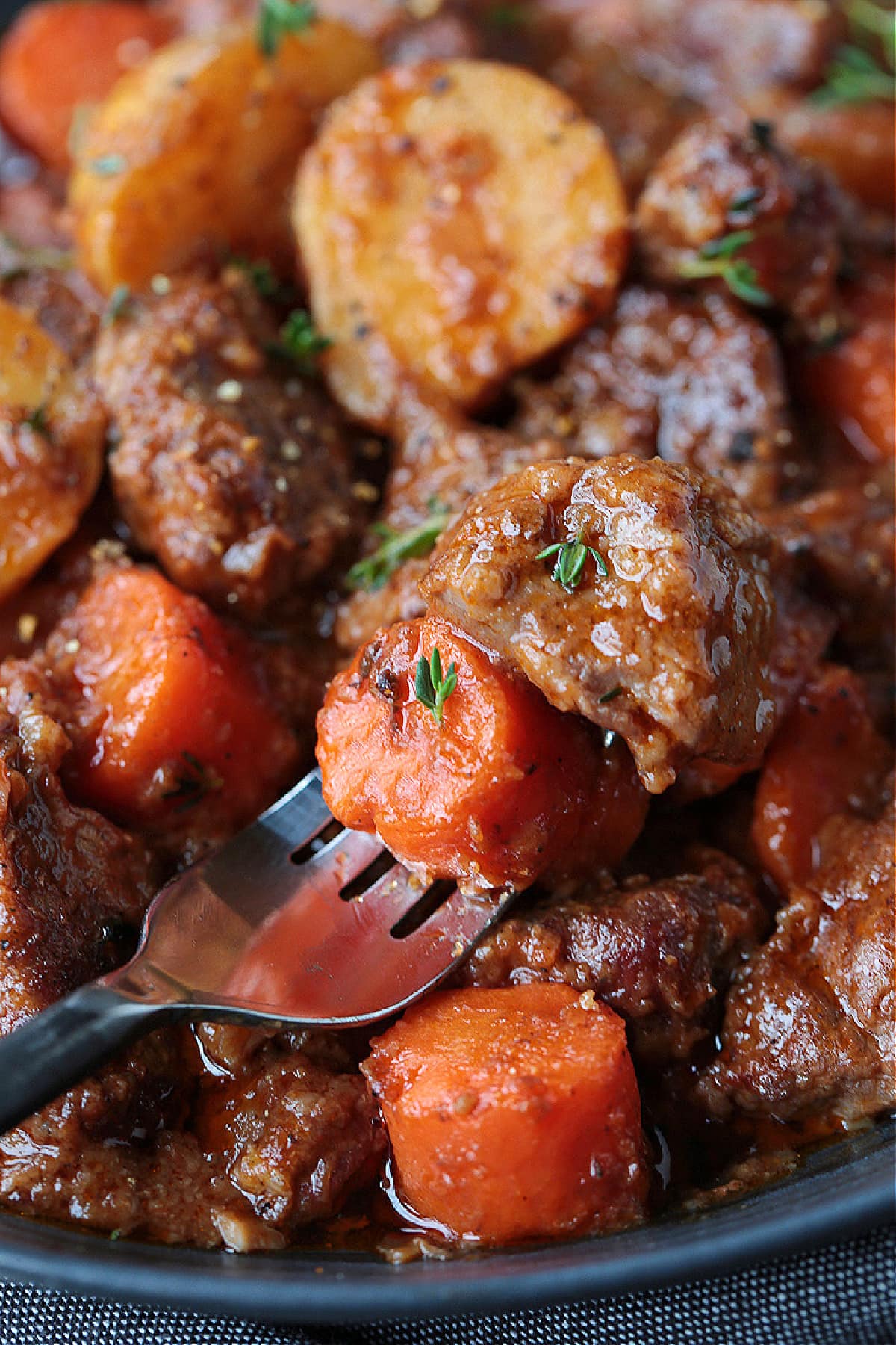 Our Easy Beef Stew is sure to become a family favorite! Tender pieces of beef and vegetables simmered in a red wine and beef gravy. beef stew on fork with carrots and potatoes