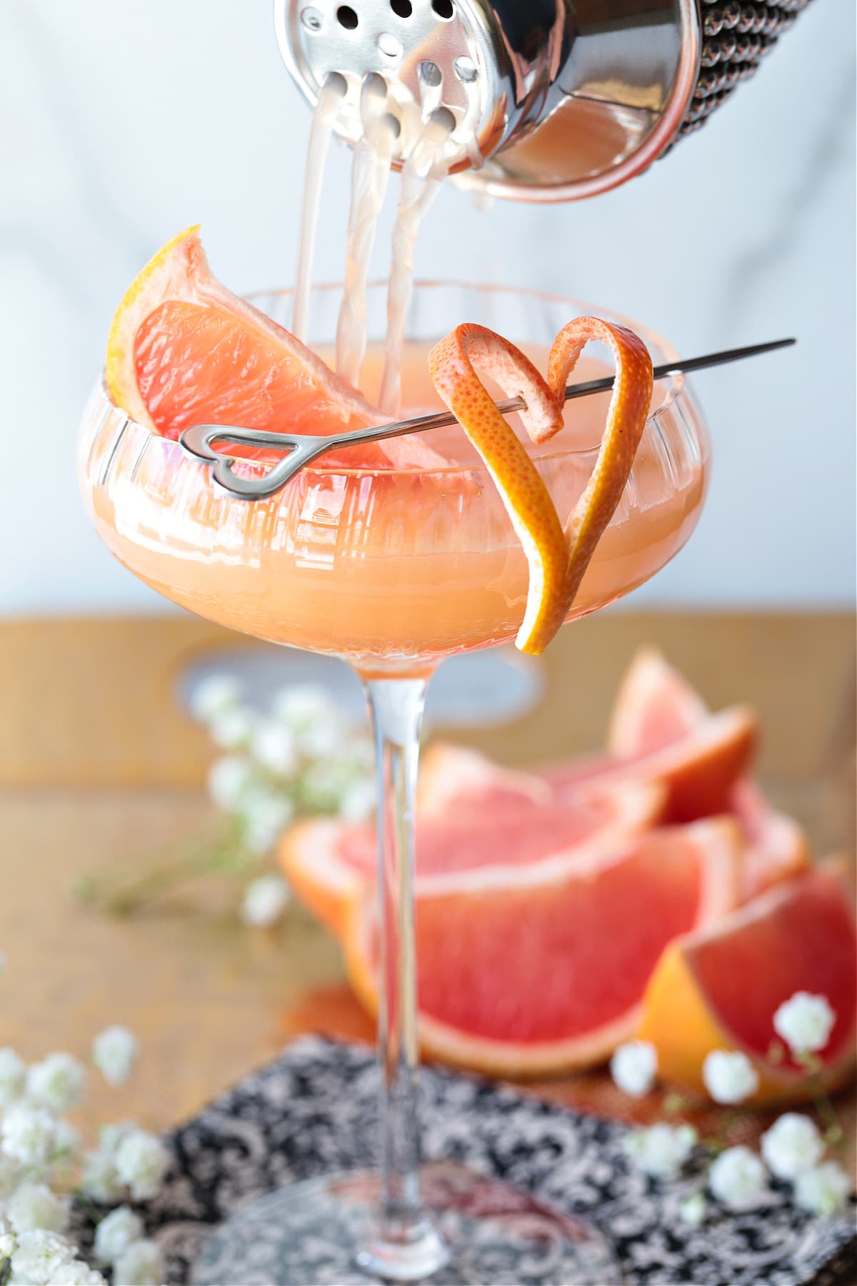 gin cocktail being poured into a coupe glass from shaker