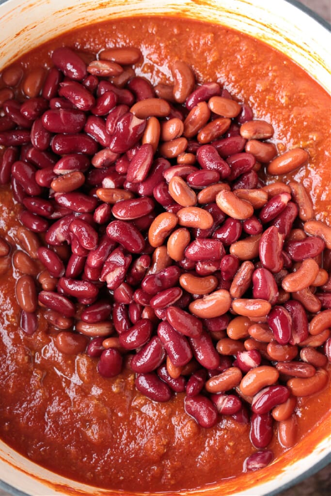 Our Ground Beef Chili recipe is loved by all! Not too spicy with big, bold flavors. Make a big batch for the week, leftovers are even better! beans in pot with tomato sauce and ground beef