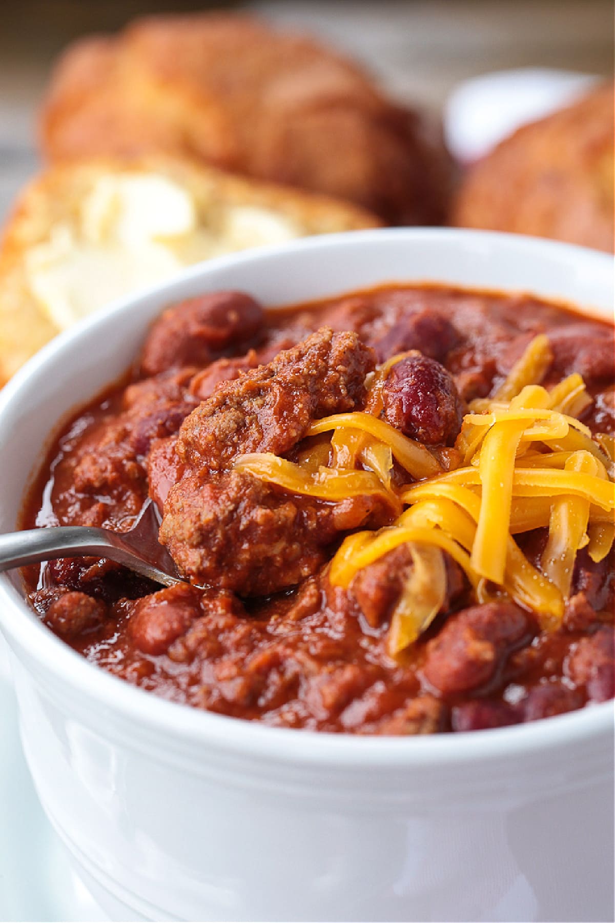 spoon in bowl of beef chili with cheese